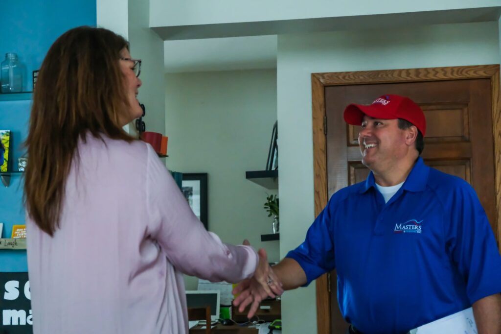 Masters Heating & Cooling technician shaking hands with a customer 