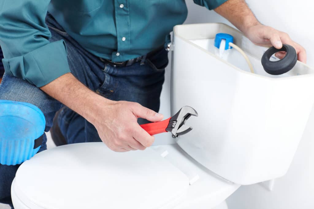 Plumber repairing a residential toilet