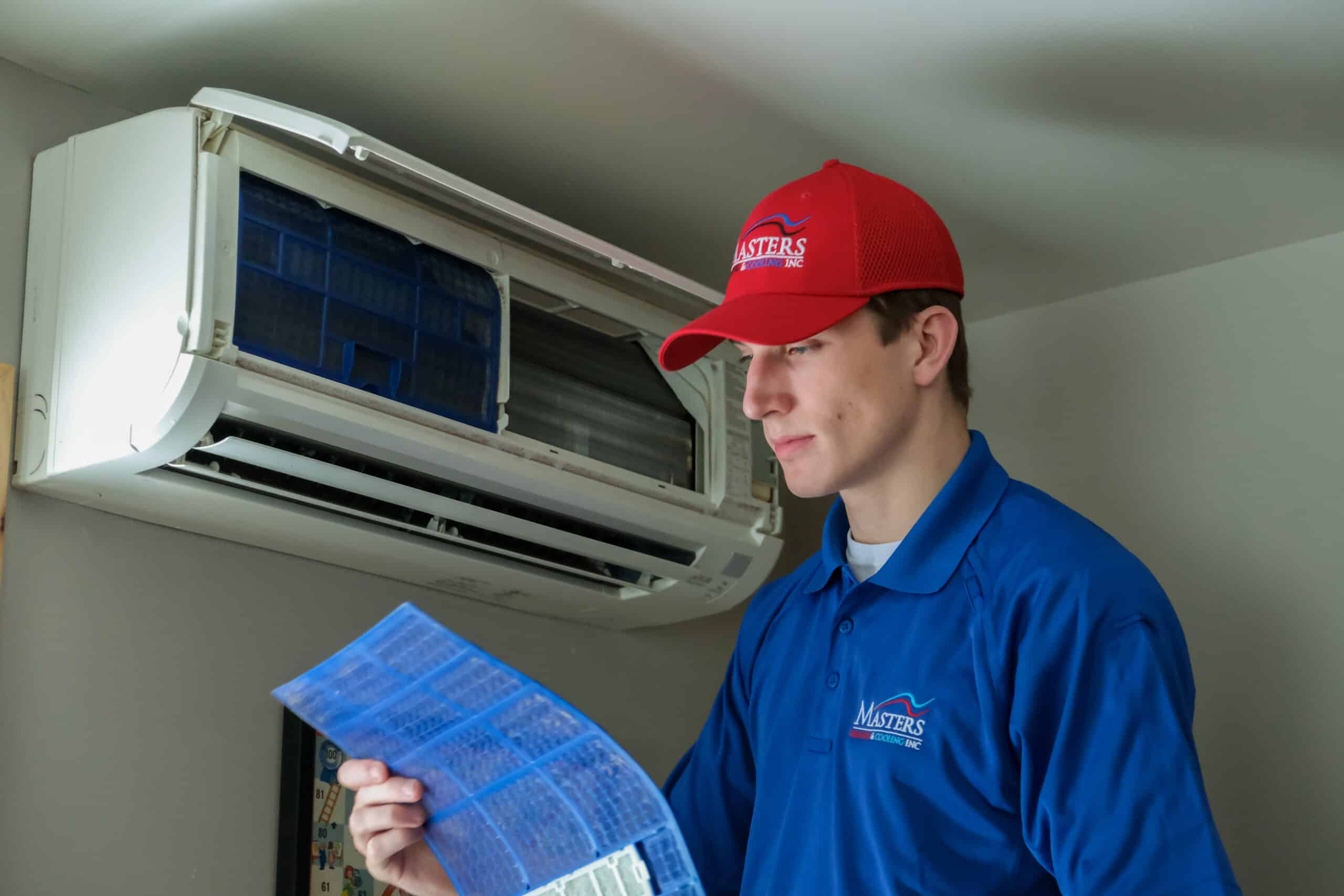 Masters Heating & Cooling technician changing the air filter of a cooling system