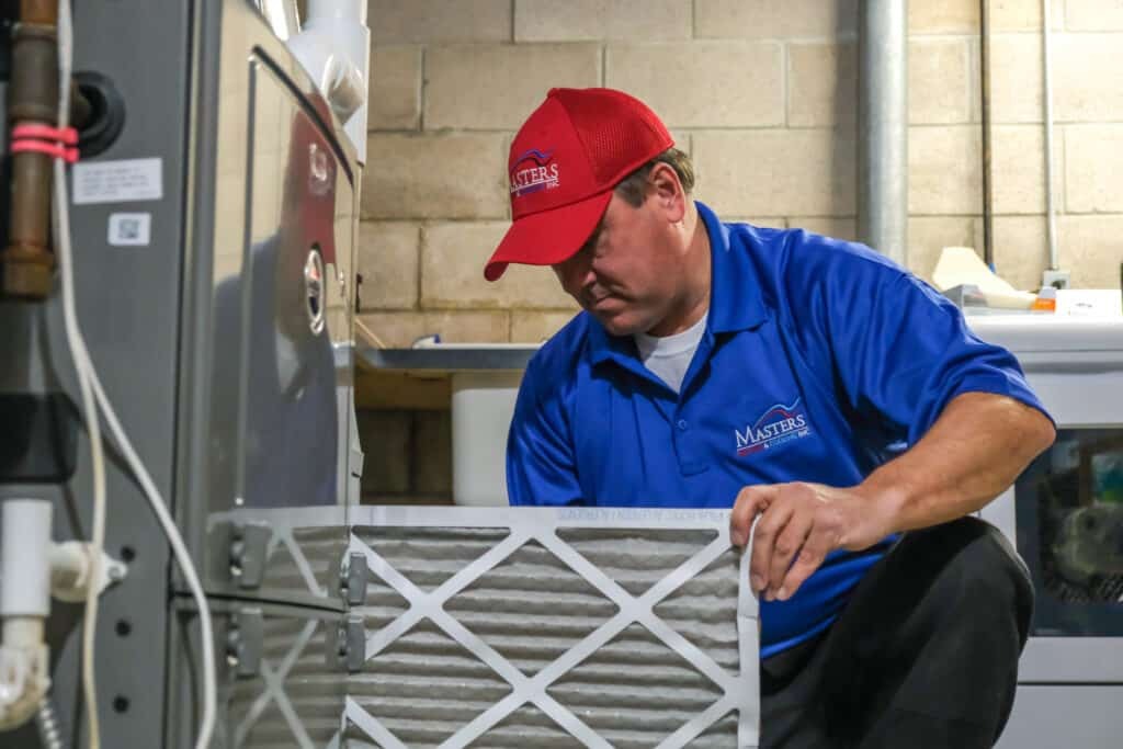 Masters Heating, Cooling, Plumbing & Electrical technician replacing a furnace air filter