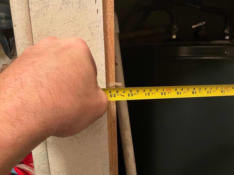 Responded to service call for leaking electric tanked water heater located in basement utility area. Upon arrival, assessed the unit installed in framed opening adjacent to storage space. Took measurements of clearance space and documented existing water heater configuration, including manufacturer specifications and energy guide labels. Photographed unit condition and surrounding installation area to document leak source and determine replacement requirements.
