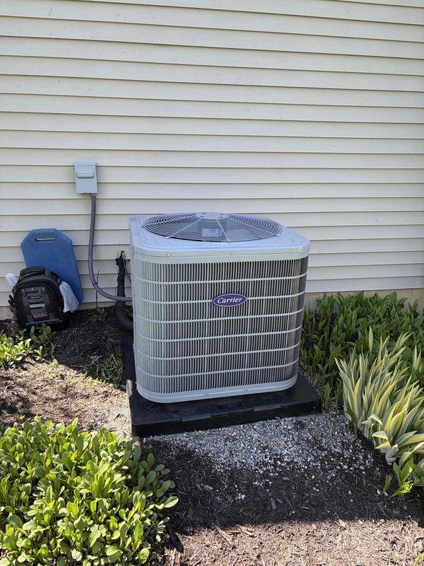 Completed preventive maintenance inspection on Carrier outdoor condensing unit. Performed comprehensive system evaluation including visual inspection of cabinet condition, noting weathering and discoloration on upper grille sections consistent with outdoor exposure. Inspected refrigerant line connections, electrical disconnect, and conduit routing. Verified proper unit mounting and levelness on base pad. Checked fan motor operation and protective grille screening integrity. Confirmed adequate clearance from landscaping and proper airflow around unit perimeter. System operational and maintenance contract extended through expiration date. Unit photographed for service records.