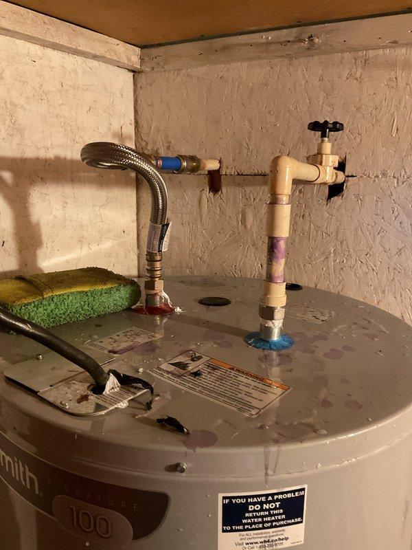 Paulding, OH - Responded to emergency water leak call at residential property. Upon arrival, performed comprehensive leak detection inspection of water heater and associated plumbing connections. Identified active leak at top-mounted pipe assembly with visible water staining and discoloration on water heater lid and rigid pipe connections. Inspected both the flexible braided stainless steel supply line with blue connector and the rigid beige pipe assembly with brass shutoff valve. Documented condition of all plumbing connections and evidence of water intrusion. Customer confirmed this was a new leak separate from previous service visit, requiring immediate attention to prevent further water damage.