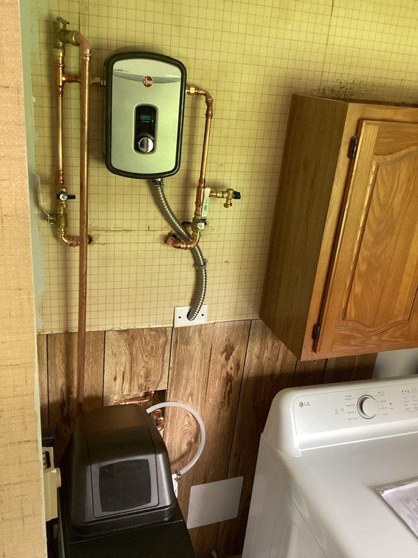 Installed a new electric tankless water heater in the utility room, including all necessary copper piping connections and electrical hookup to provide on-demand hot water. Also installed a water softener system with supply and drain lines, positioning both units for optimal access and operation within the existing laundry area plumbing configuration.