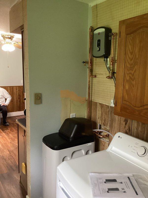 Installed a new electric tankless water heater in the utility room, including all necessary copper piping connections and electrical hookup to provide on-demand hot water. Also installed a water softener system with supply and drain lines, positioning both units for optimal access and operation within the existing laundry area plumbing configuration.
