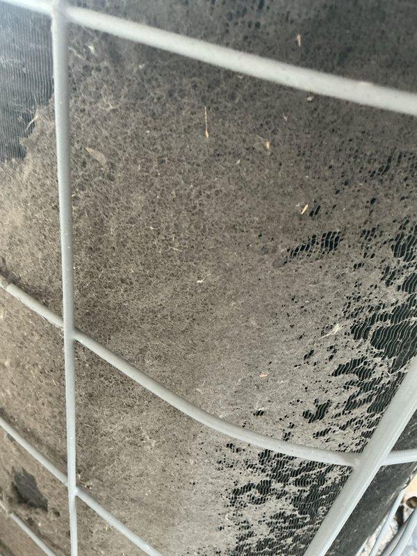 Responded to no cooling complaint on Unit 4. Upon inspection, found outdoor condenser unit with severely contaminated coil fins showing heavy dirt, debris, and grime accumulation restricting airflow. Return air filter system exhibited excessive dust buildup with thick gray coating obscuring filter material, significantly reducing system airflow and efficiency. Cleaned condenser coils, replaced dirty air filter, and restored unit to proper cooling operation. System tested and confirmed operational following maintenance.