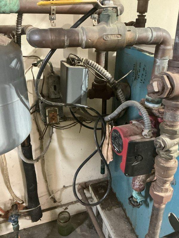 Completed estimate for gas boiler replacement in garage mechanical room. Assessed existing hydronic heating system showing significant age-related deterioration including corroded piping, rusted expansion tank, and aged circulation pump. Documented current installation featuring galvanized steel piping with surface oxidation, blue expansion tank with visible rust staining, red/black circulation pump, water filtration system, and various control valves in deteriorated condition. Provided comprehensive replacement recommendations and captured photographic documentation of all equipment and components for customer review.