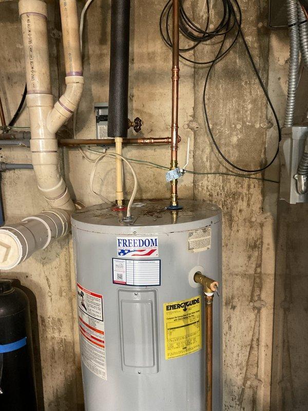 Angola, IN - Responded to service call for leaking tanked electric water heater in basement utility area. Upon inspection, identified leak at fitting connection on copper piping at top of Freedom-brand electric water heater unit. Repaired leaking fitting to restore proper seal and eliminate water loss. Provided information regarding electric tankless water heater options as alternative solution for future consideration.