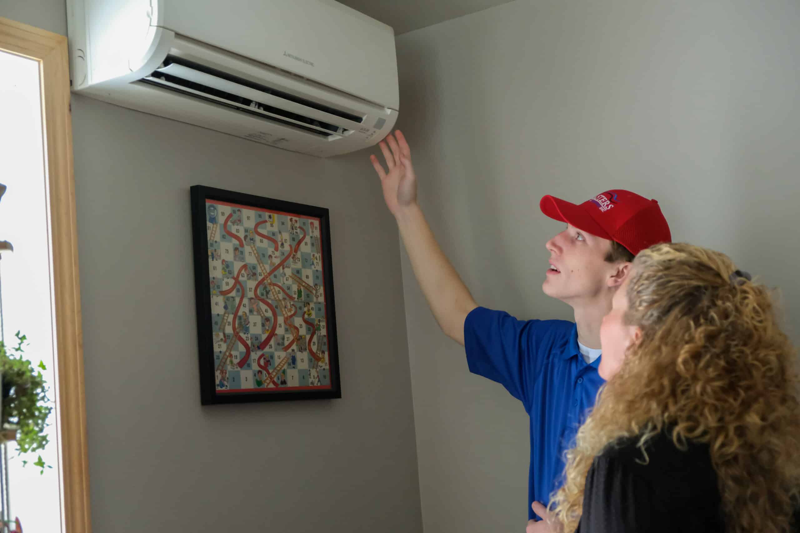 Masters Heating & Cooling technician showing a homeowner their new ductless mini-split 