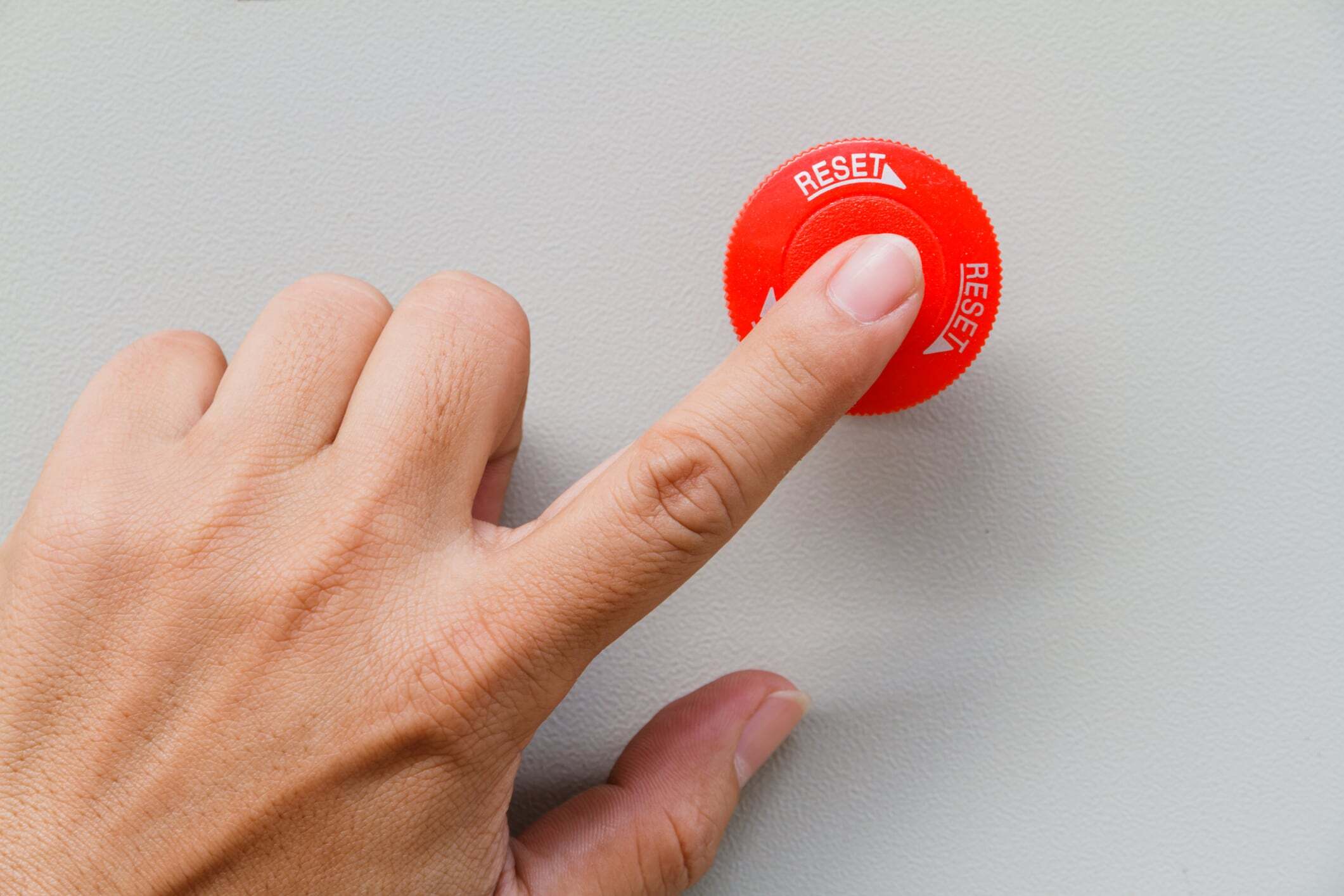 Woman’s finger on a red reset button