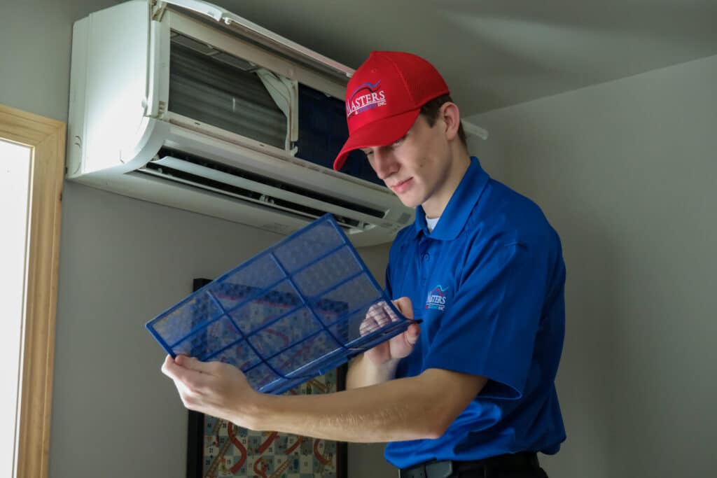 Masters Heating, Cooling, Plumbing & Electrical technician servicing a home's ductless AC