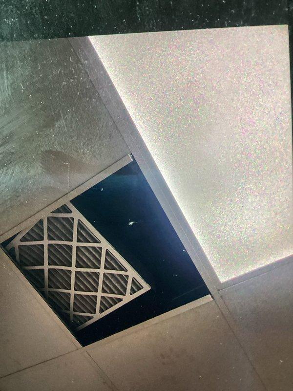 Responded to no cooling complaint at commercial shop with indoor temperature at 80°F. Upon arrival, found system had been shut off by customer after they attempted filter change, which resulted in supply grille and condensate drain line becoming disconnected. Inspected ceiling-mounted air handler, reinstalled dirty pleated filter properly, secured supply air grille back into drop ceiling grid, and reconnected condensate drain tubing to prevent water damage. Instructed customer on proper filter replacement procedure to avoid future issues, started system, and verified unit now operating correctly with cool air delivery restored.