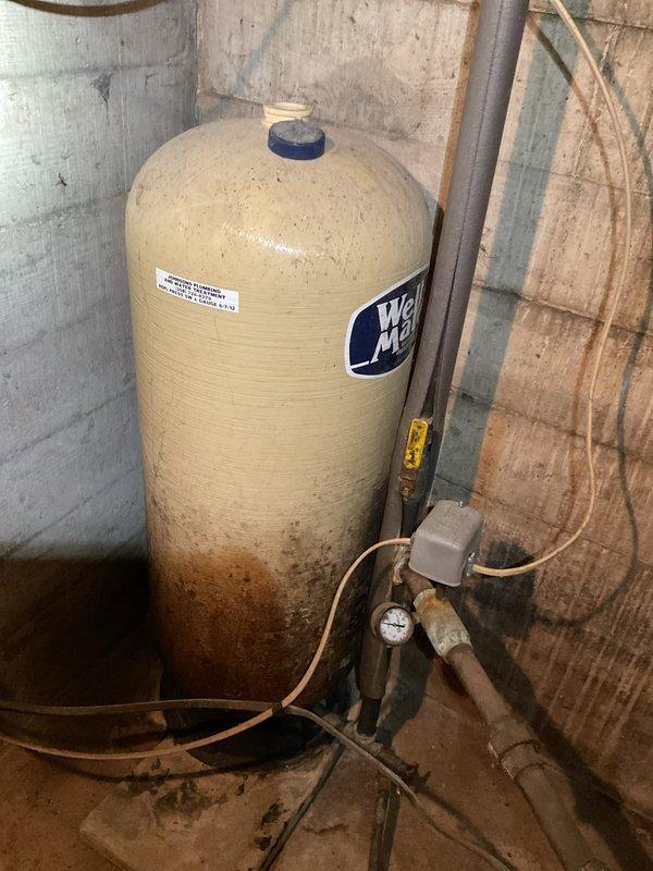 Decatur, IN - Responded to service call for well pump cycling on and off frequently. Upon inspection, diagnosed failed bladder in pressure tank located in basement. Observed significant rust staining and corrosion at tank base indicating age and deterioration. Found existing well shutoff valve seized due to corrosion, preventing isolation of system. Documented existing conditions including pressure gauge, piping connections, and electrical components with photographs for customer records.